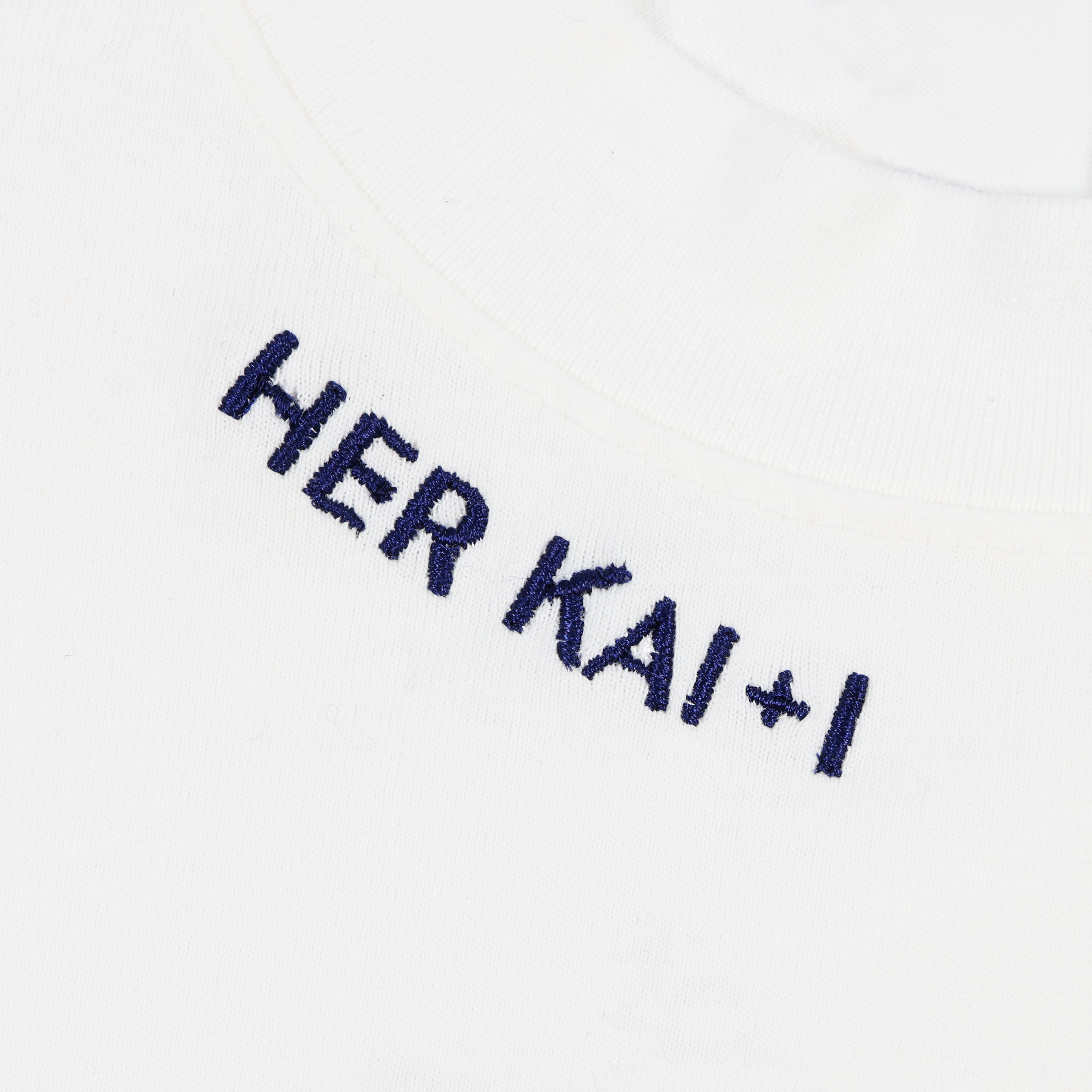 Detail view of Her kai & I logo embroidery along neckline